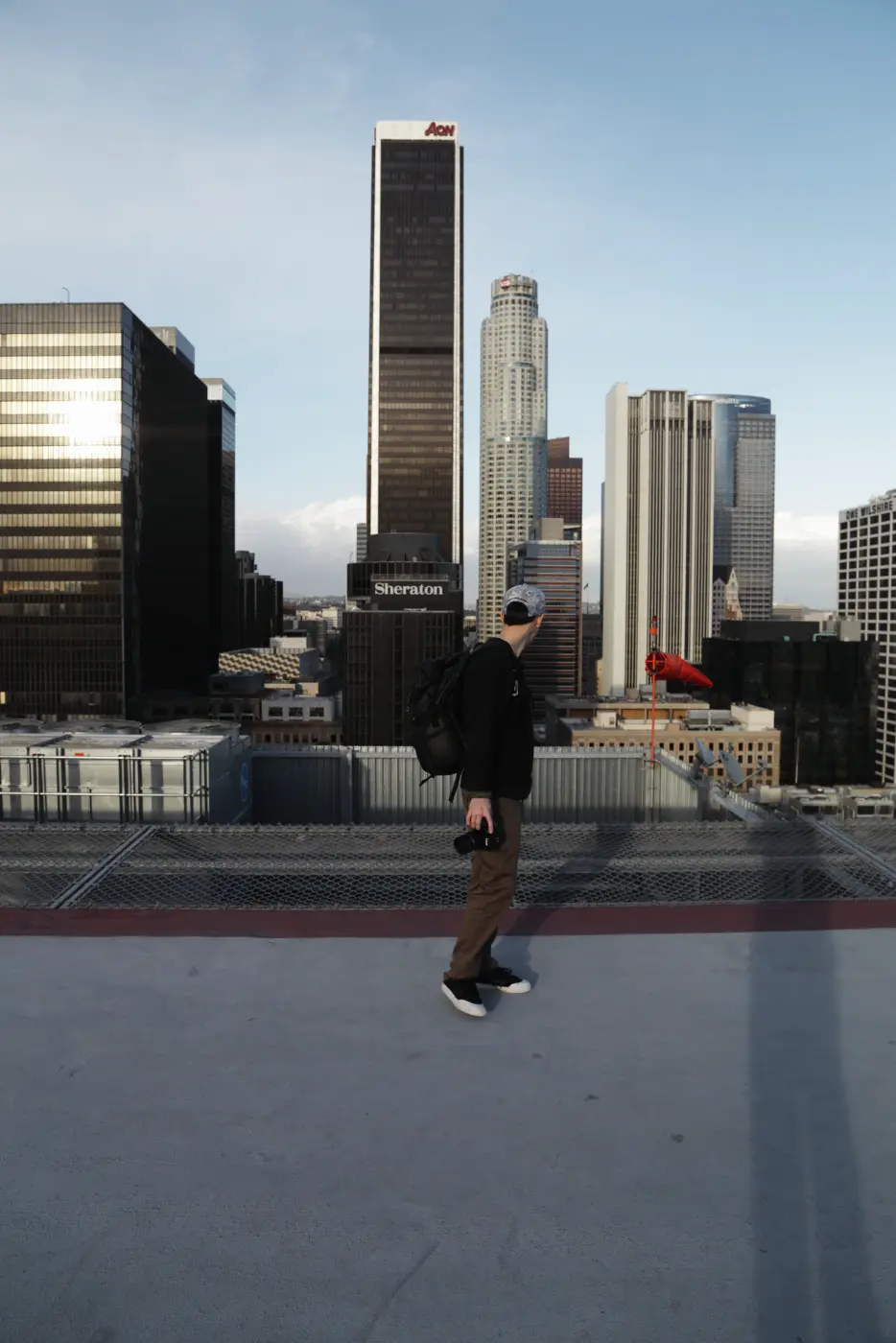 Documentary example: man with a camera on a rooftop below city towers